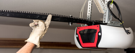 Hand touching the chain on a chain-drive garage door opener